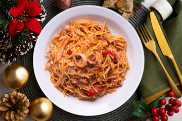 Fideua with squid and seafood. Typical Spanish tapa cooked with paella. Christmas food served on a table decorated with Christmas motifs.