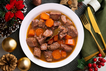 Beef stew with carrots. Traditional tapa from the central area of Spain.. Christmas food served on a table decorated with Christmas motifs.