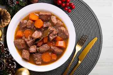 Beef stew with carrots. Traditional tapa from the central area of Spain.. Christmas food served on a table decorated with Christmas motifs.