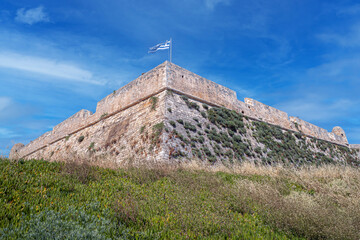 Fototapeta na wymiar National Greek flag fluttering from the Venetian Fortezza Castle, Rethymno, Crete, Greece
