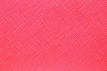 Seamless plastic texture background. Close-up of a detail from a red surface of a cosmetic bag. Beautiful backdrop. Macro.