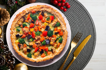 Veggie quiche traditional french recipe on puff pastry. Christmas food served on a table decorated with Christmas motifs.