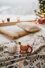Cocoa with marshmallows on a wooden floor with Christmas tree on the background.