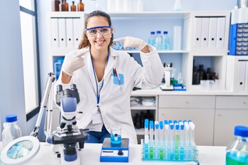 Fototapeta premium Young hispanic woman working at scientist laboratory smiling cheerful showing and pointing with fingers teeth and mouth. dental health concept.