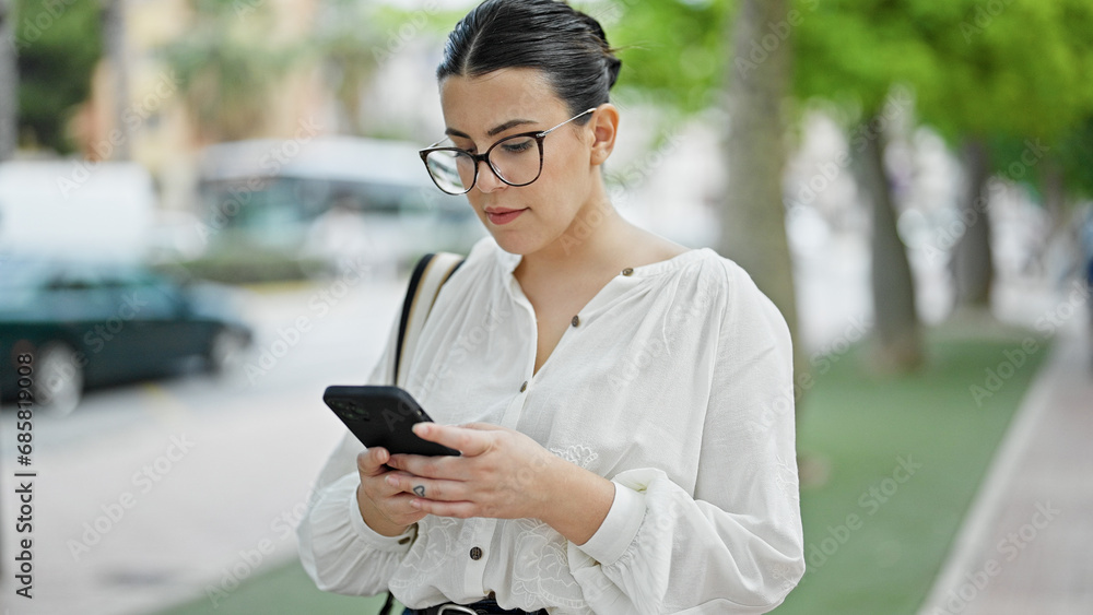 Wall mural Young beautiful hispanic woman using smartphone at street