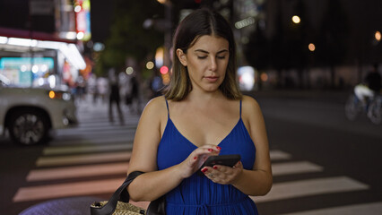 Beautiful hispanic woman waiting for taxi on tokyo's streets at night, using phone app and enjoying city lights