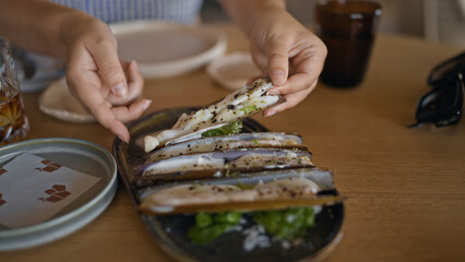 Young hispanic woman eating razor shells at the restaurant