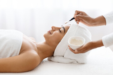 Young indian lady getting facial treatment at spa salon