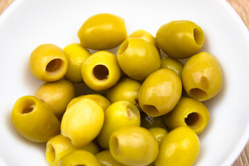 Green olives in a cup. Pitted green olives in a white cup on the table. Canned olives, recipe, food.