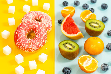 Healthy and unhealthy sugar, yellow blue background, juicy fruits next to sweet donut and processed...