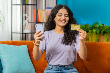 Indian woman use credit bank card and smartphone while transferring money, purchases online...