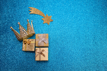 Epiphany Day or Dia de Reyes Magos concept. Gold crown and gifts on blue sparkling background