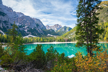 Fototapeta na wymiar Green-blue lake amid mountains and a forest of pines, spruce and larch in the Dolomites of Italy