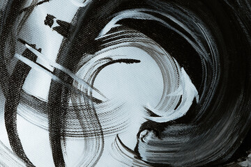 Dark brush strokes on a textured canvas. Black and white abstract background. A fragment of an abstract painting created in an art studio. A stroke of oil paint on linen.
