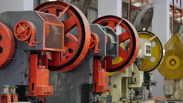 Industrial Stamping Presses: A row of large, heavy-duty industrial stamping presses, with prominent red and yellow gears, stands ready for production in a manufacturing facility.