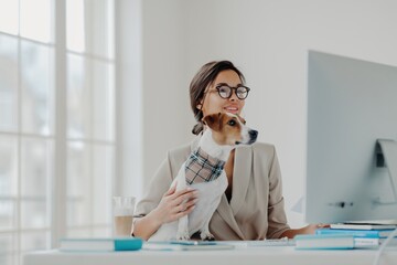 Focused businesswoman with her dog at a bright workstation, a blend of professional life and pet...