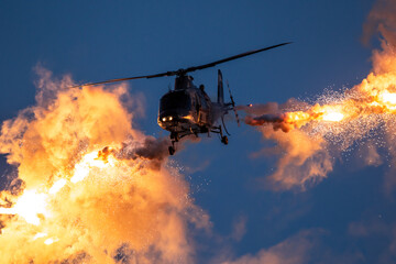 Military helicopter in flight firing off flare decoys at night. - 685836837
