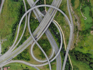 Aerial view of a complex highway interchange with intertwined roads and green areas.