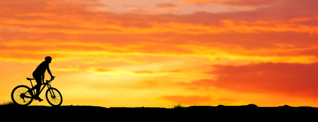Silhouette of a mountain biker enjoying downhill during the sunset. Mountain bike concept. Mountain...
