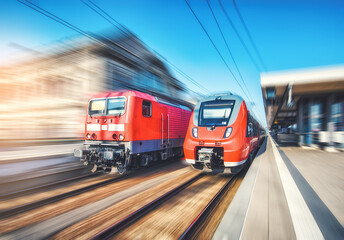 Red high speed trains in motion on the railway station at sunset. Fast modern intercity train and...