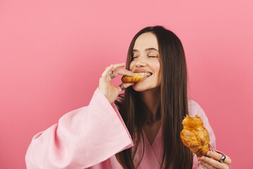 Brunette happy woman having a relaxing moment breaking her croissant at small piece and eat it....