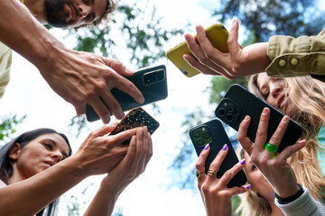 Close-up of a diverse group using smartphones to capture or share a moment in a park setting