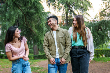 Obraz premium Three joyful friends share a laugh in a park, enjoying a cheerful moment together outdoors.