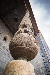 Carved wood column and stone pillar in the ancient city of Khiva in Khorezm, wood carving and stone...