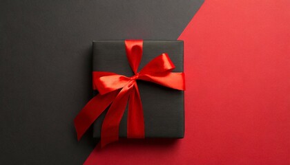top view photo of black giftbox with vivid red ribbon bow on two color red and black background with copyspace