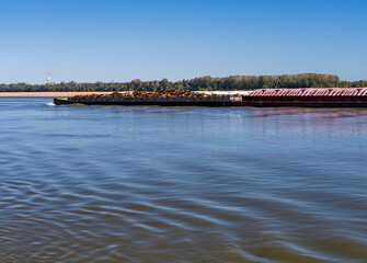 Large tug boat pushing rows of barges with scrap metal and grain products up the Mississippi river...