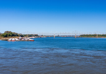 Fototapeta na wymiar Barges wait at the confluence of the blue Ohio river and brown Mississippi river at Cairo with blue and brown muddy streams mixing