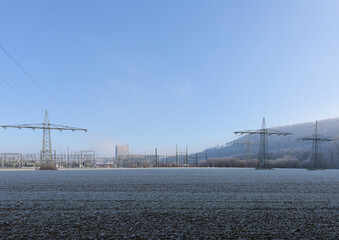 Power lines at a power station of an old nuclear power plant in winter with snow on a field and a...