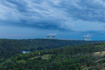 Dukovany nuclear power plant in the Czech Republic, Europe. Smoke cooling towers. There are clouds in the sky. In the foreground is the nature of the Highlands.