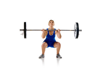 Fototapeta na wymiar Concentrated strong young woman, athlete training doing squats, lifting heavy barbell against white background. Concept of sport, strength, gym, healthy lifestyle, power and endurance, weightlifting.