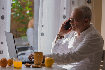 Fototapeta na wymiar mature man working while having breakfast at home or workplace
