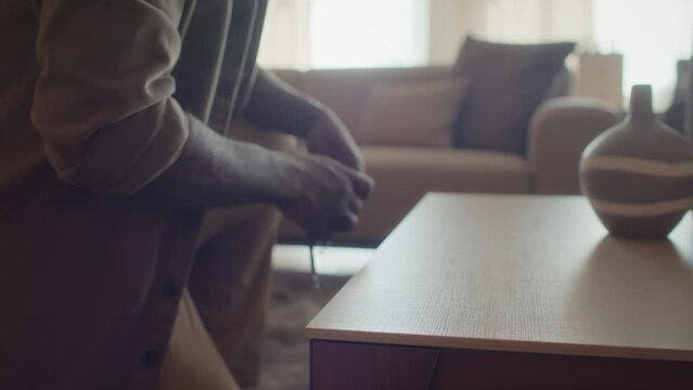 Selective focus on unrecognizable man using tape measure on small wooden coffee table in furniture store