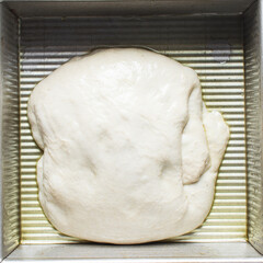 Focaccia dough in a square baking tin, process of making focaccia, dough rising in a baking pan