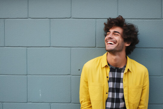 Joyful Laughter: Young Man in Yellow Jacket Against Blue Wall