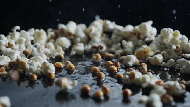 Popcorn is cooked in a frying pan with sunflower oil on black background shooting with high speed camera
