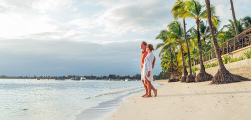 Couple in love hugging on sandy exotic beach while having evening walk by Trou-aux-Biches seashore...