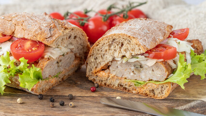 Sliced sandwich with grilled minced meat closeup on wooden cutting board. Kofta sandwich with sauce, sliced cabbage, onion, lettuce salad leaves and tomato.