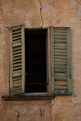 Fototapeta na wymiar An old window in an old Italian facade wall with one shutter open