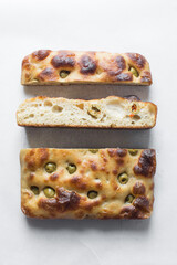 cross-section of homemade olive focaccia on a white background, Flatlay of focaccia with green olive topping, fresh homemade focaccia bread	