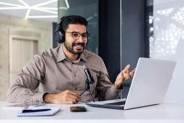 Businessman recording training video online course, man smiling in talking using professional microphone and laptop, working inside office, successful business coach, and financier. - obrazy, fototapety, plakaty