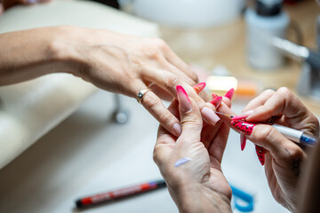 Close-up shot of a woman hand in a nail salon receiving manicure by beautician with brush. Woman...