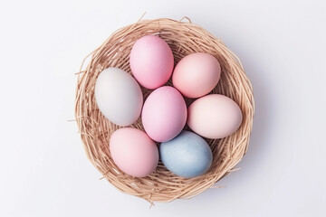 Pastel pink and blue Easter eggs in a nest on the white background. Top view spring backdrop.