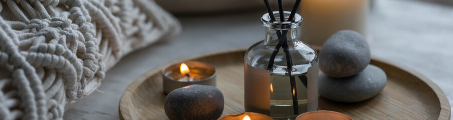 Burning candles on bamboo tray, cozy home atmosphere. Relaxation, detention zone in the living or bedroom. Stones, sea shells as decor. Apartment natural aroma diffusor ocean breeze fragrance. Banner