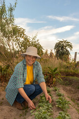 mujer sentada en medio de su huerta sonriendo a la camara con espacio para texto sacando rabanos de...