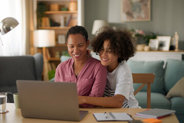Mother and teenage son using a laptop together at home - Powered by Adobe