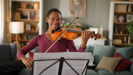 Mid adult woman playing violin at home